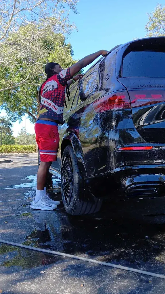 Detailer washing a black Maybach SUV during a mobile car wash